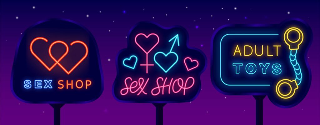 Bright neon signs for a sex shop and adult toys on a dark purple background.