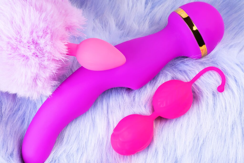 A set of pink silicone wellness accessories placed on soft, fluffy fabric.